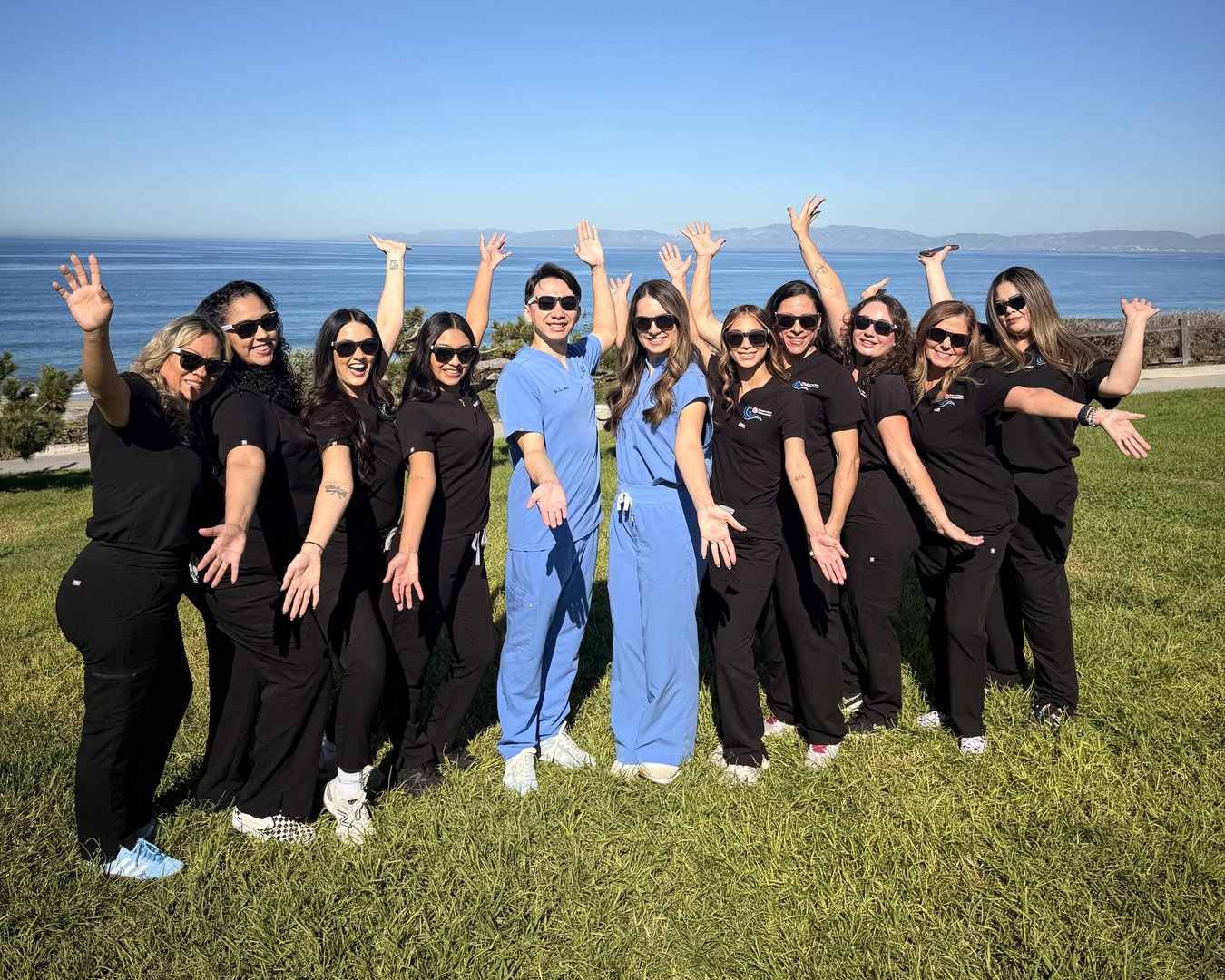 Beach Cities Orthodontics team in Torrance, CA smiling in sunglasses on an ocean-view lawn